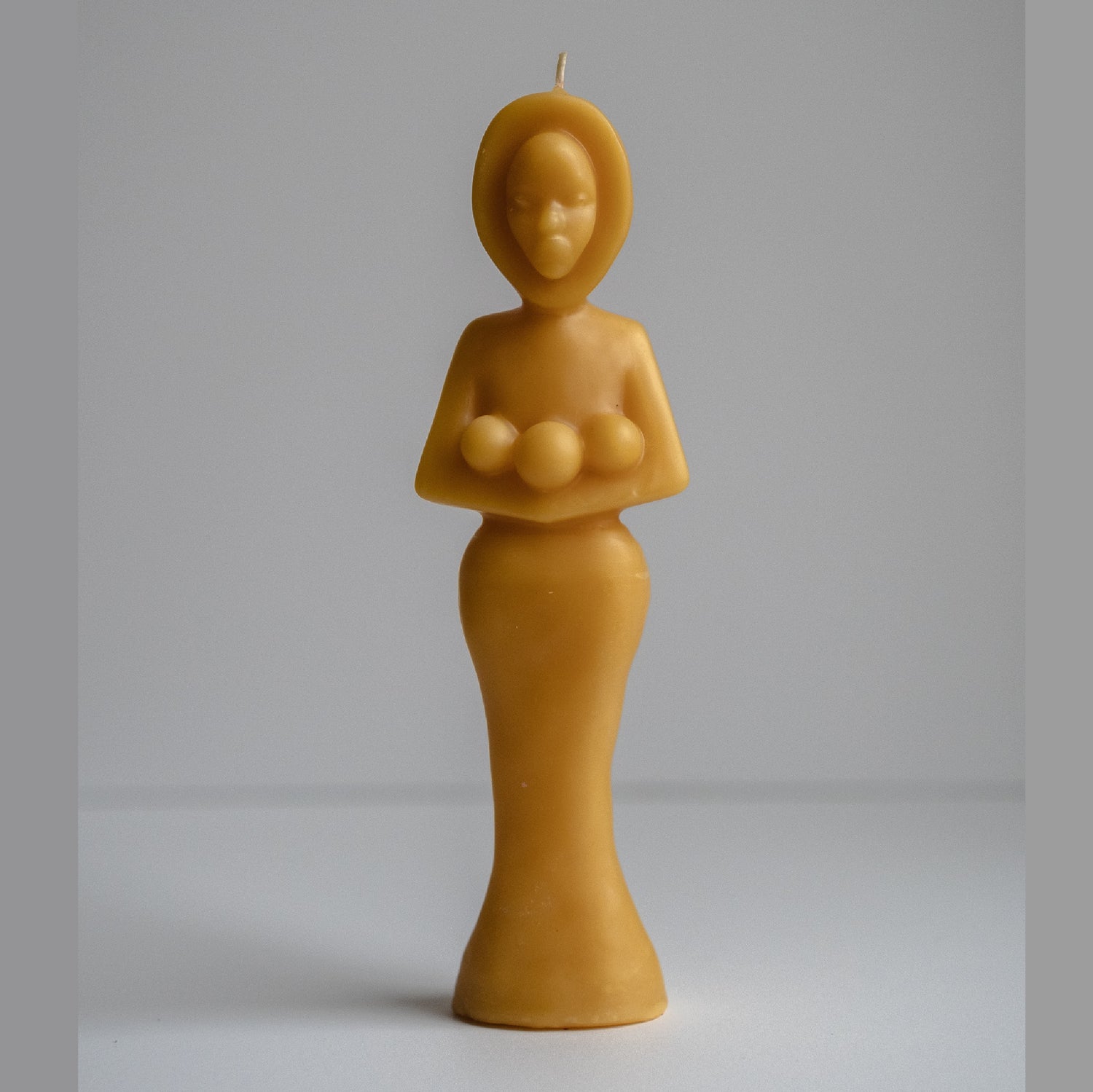 Beeswax candle sculpture of a cloaked, hooded figure holding three orbs. Appears definitively religious, though not apparent to which religion it could belong.